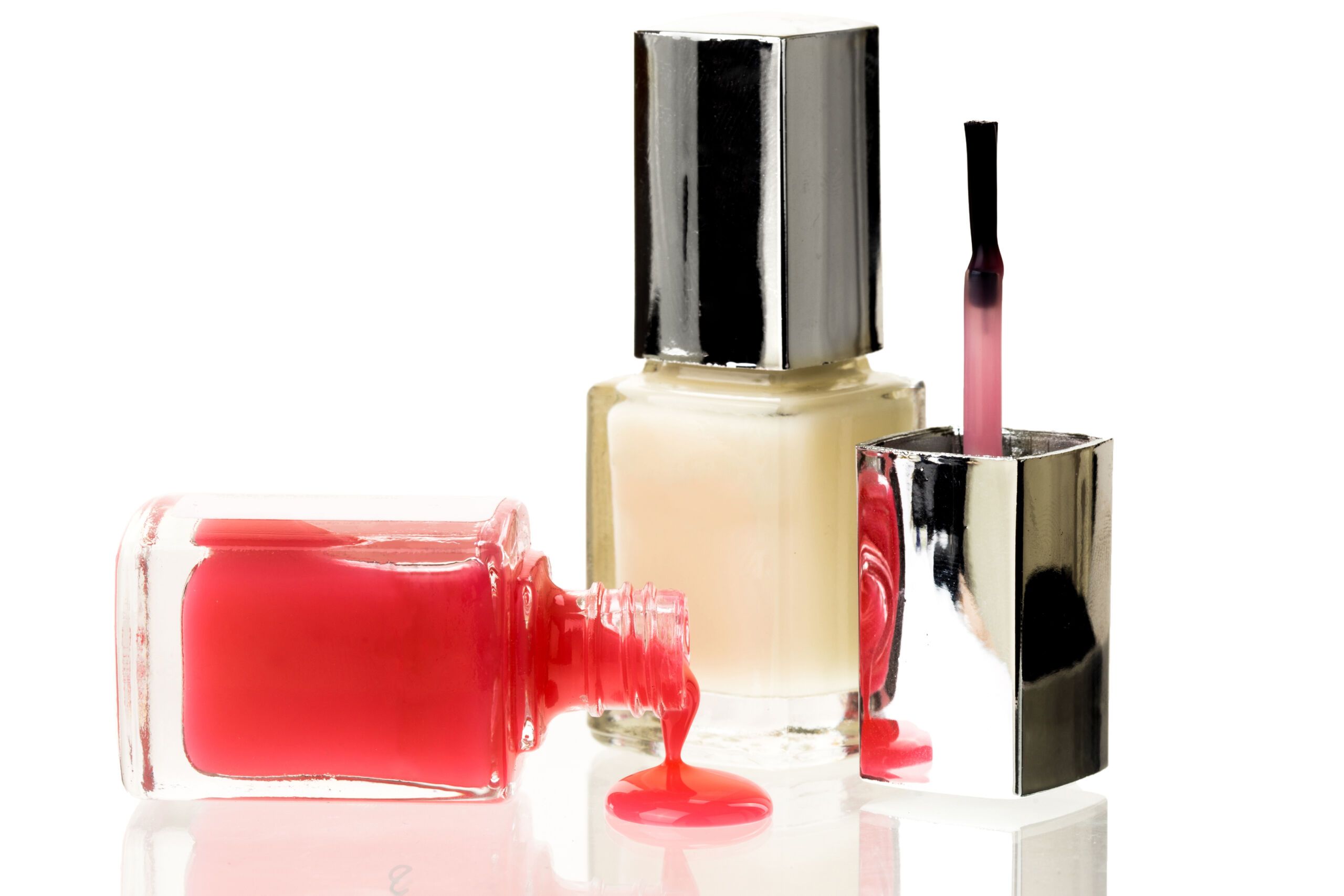 Nail color bottles spilled on white background